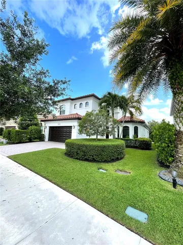 a view of a house with a big yard potted plants and large tree