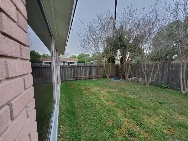 a view of a backyard with large trees and wooden fence