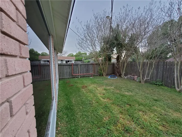 a view of a backyard with large trees and wooden fence