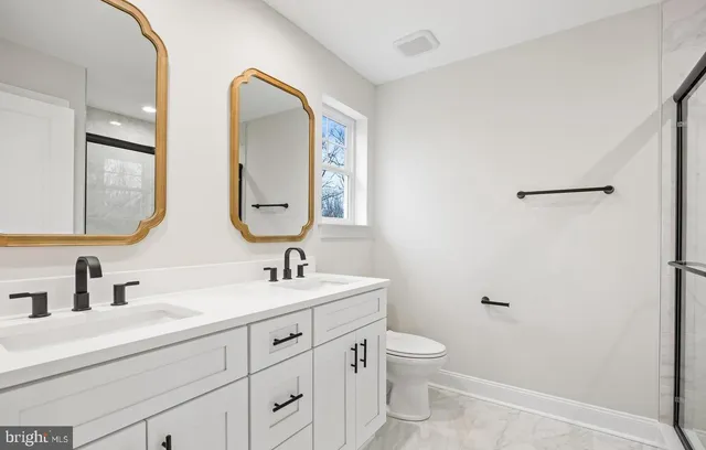 a bathroom with a double vanity sink mirror and toilet