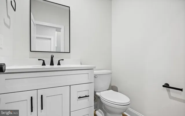 a bathroom with a toilet sink vanity and mirror