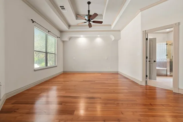 a view of empty room with wooden floor and fan