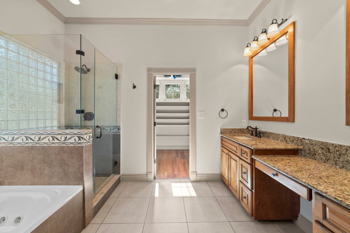 139 Ware Drive Buda, TX 78610 - Photo 28 of 40 a bathroom with a granite countertop sink a mirror and a bathtub