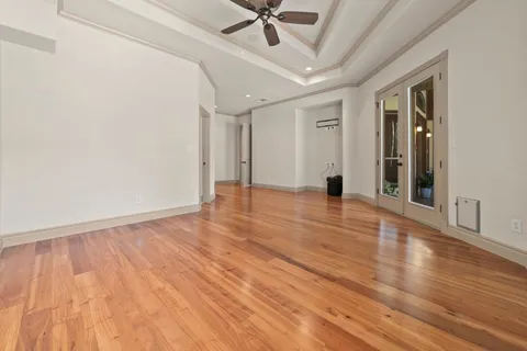 a view of an empty room with wooden floor and a ceiling fan