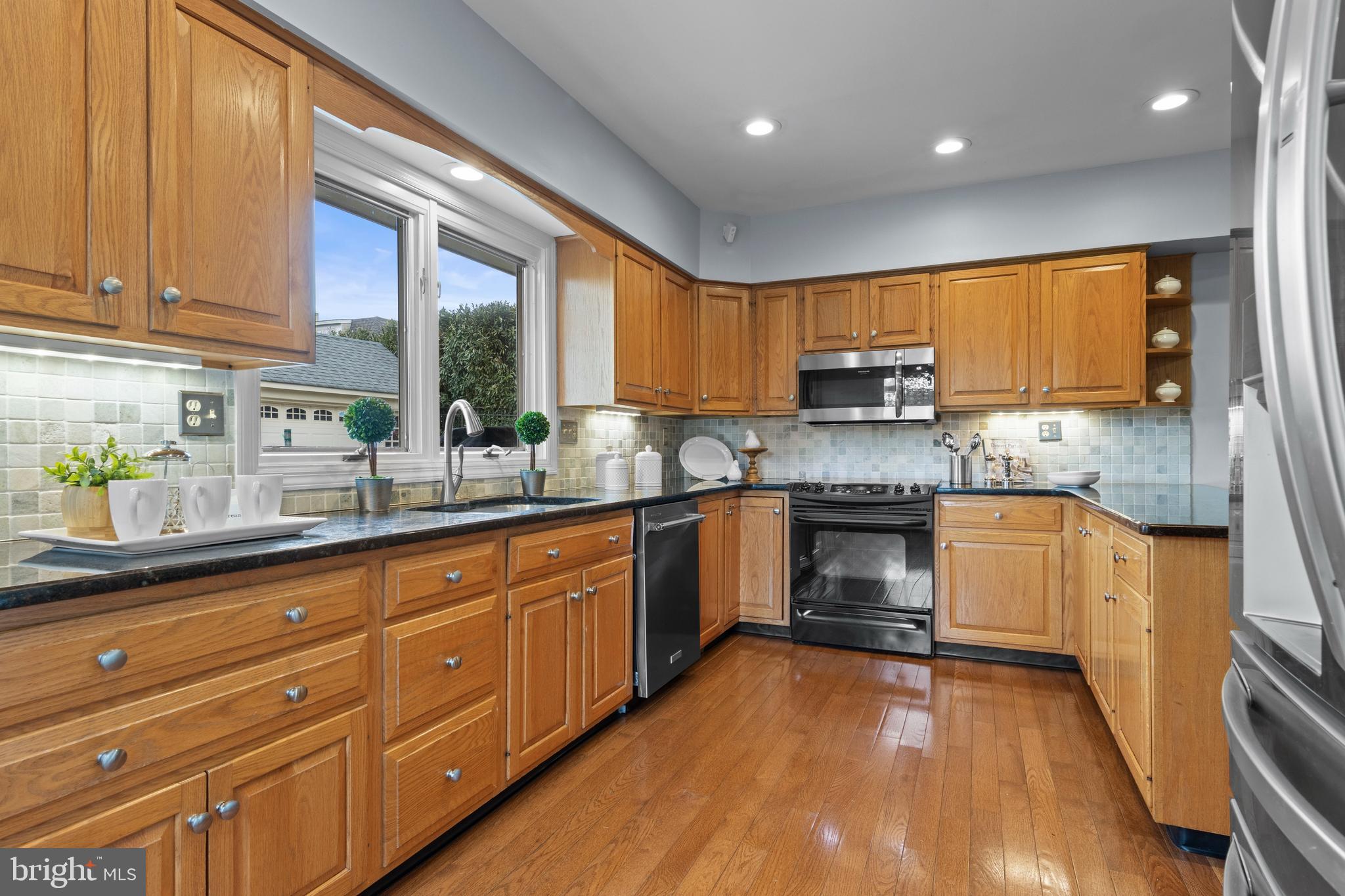 421 St Davids Road Wayne, PA 19087 - Photo 17 of 39 a kitchen with granite countertop wooden floors stainless steel appliances a sink and a window