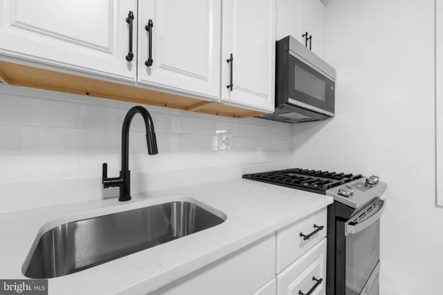 a kitchen with stainless steel appliances granite countertop a stove a sink and a microwave