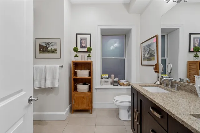 a spacious bathroom with a granite countertop sink a toilet and a mirror