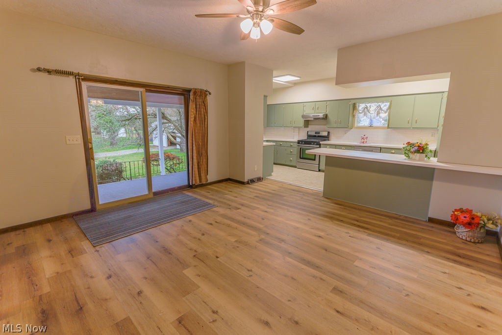 51883 Telegraph Road Amherst, OH 44001 - Photo 4 of 49 Kitchen featuring green cabinetry, kitchen peninsula, gas range, ceiling fan, and light wood-type flooring