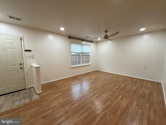 an empty room with wooden floor and a ceiling fan