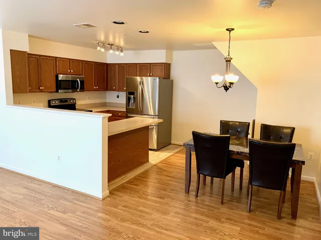 a kitchen with stainless steel appliances a table chairs and wooden floor