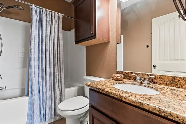 a bathroom with a granite countertop sink toilet and mirror
