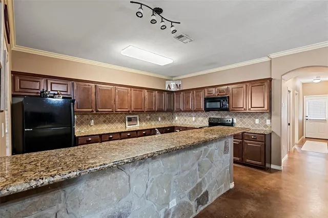 a kitchen with stainless steel appliances granite countertop a stove a sink and a refrigerator