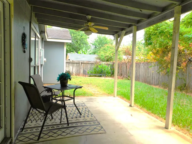 a view of backyard with a table and chairs and floor to ceiling window with garden