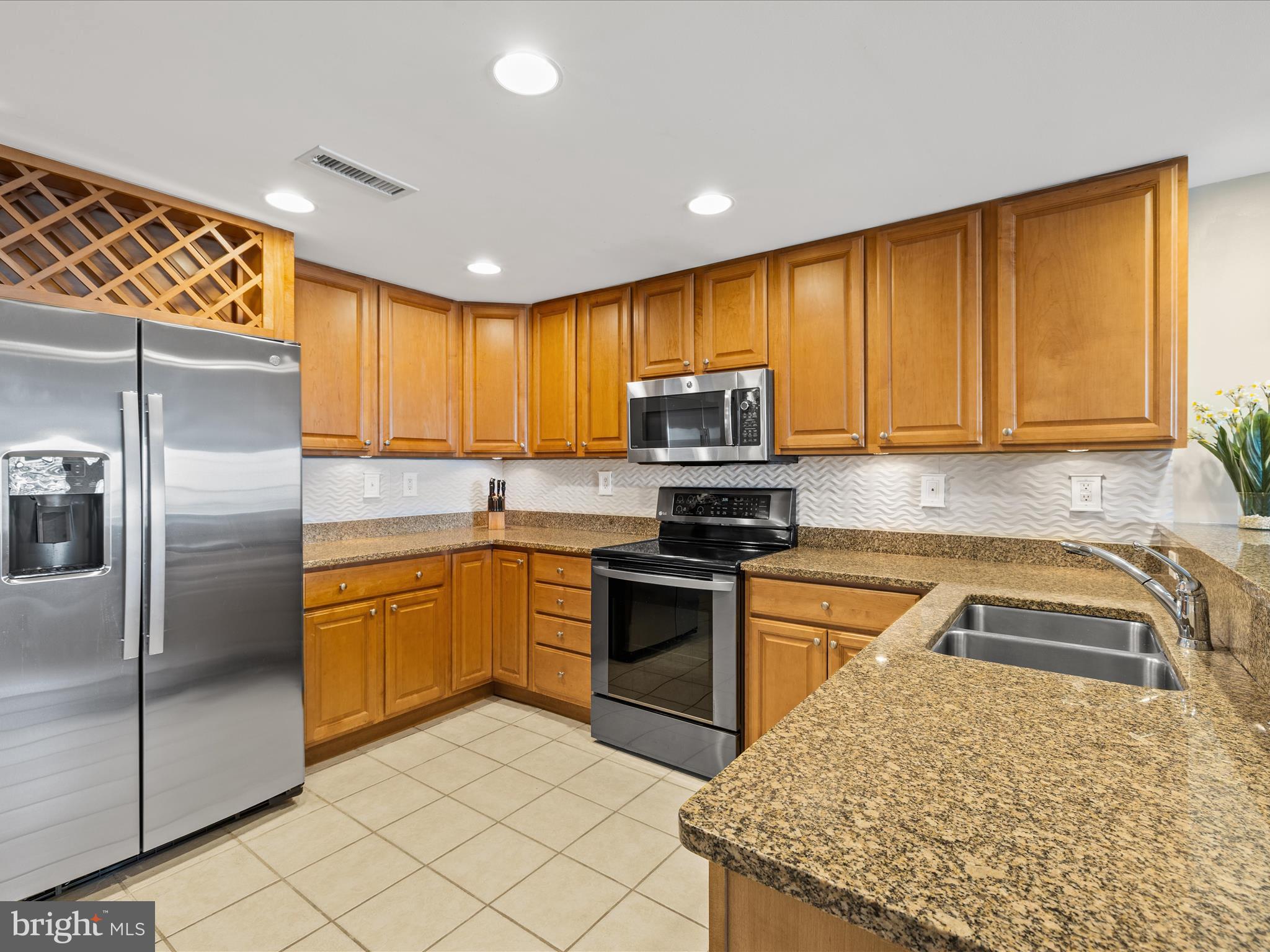 11900 Coastal Highway, Unit 102 Ocean City, MD 21842 - Photo 9 of 39 a kitchen with stainless steel appliances granite countertop a sink a stove a refrigerator a washer dryer and white cabinets