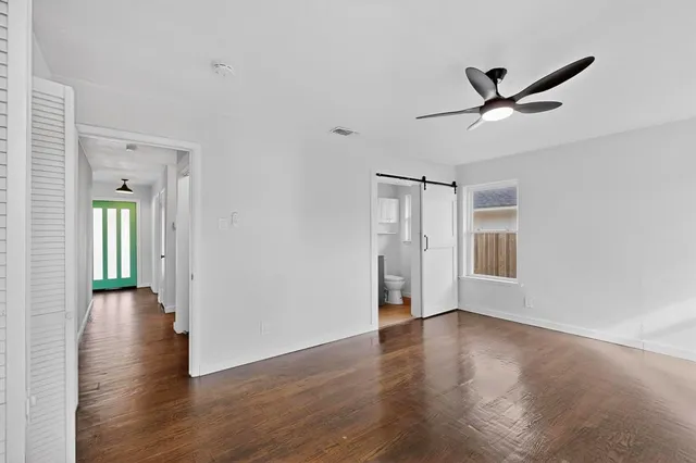 a view of an empty room with wooden floor and a ceiling fan