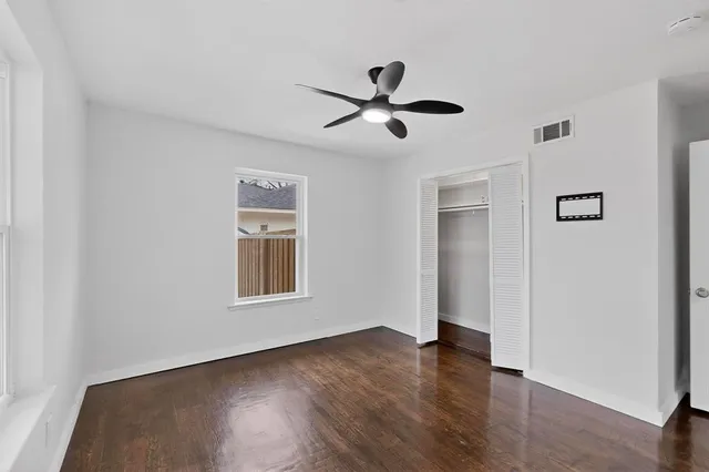 a view of empty room with wooden floor and fan