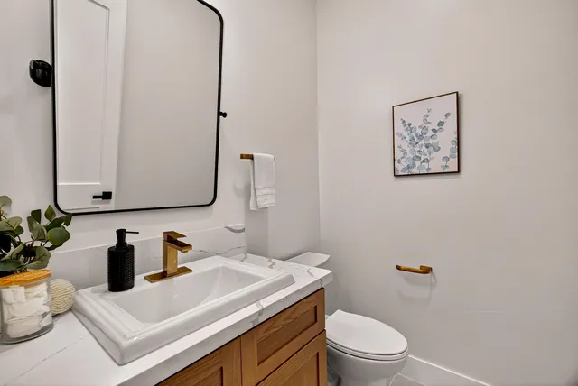 a bathroom with a granite countertop sink mirror vanity and toilet