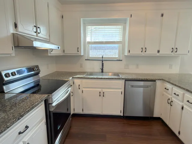 a kitchen with cabinets appliances a sink and a window