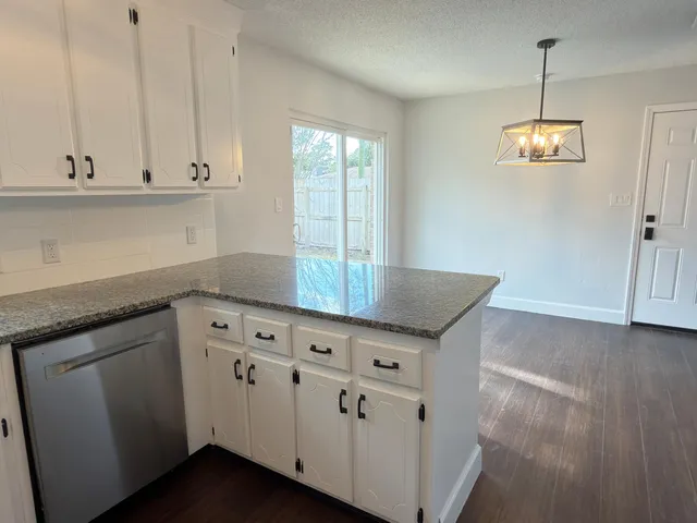 a kitchen with granite countertop white cabinets and wooden floor