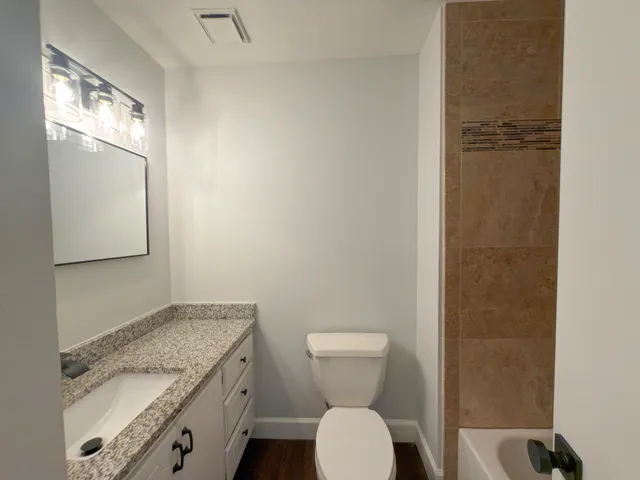 an empty room with wooden floor cabinet and ceiling fan