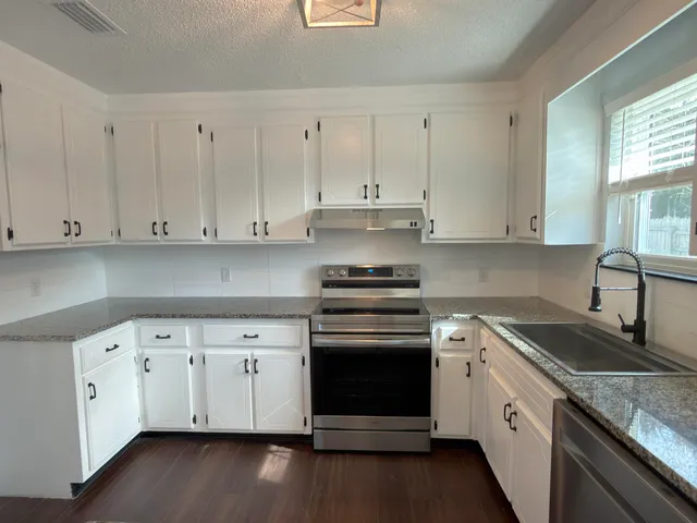a kitchen with granite countertop white cabinets and white appliances