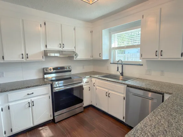 a kitchen with granite countertop white cabinets and white appliances