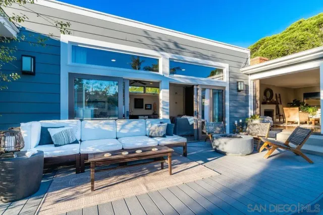 a view of a patio with couches and table and chairs with wooden fence and plants