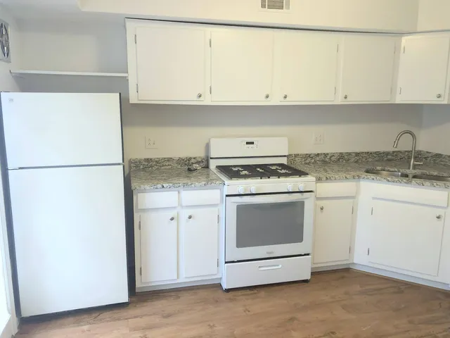 a kitchen with granite countertop white cabinets and a stove with a refrigerator