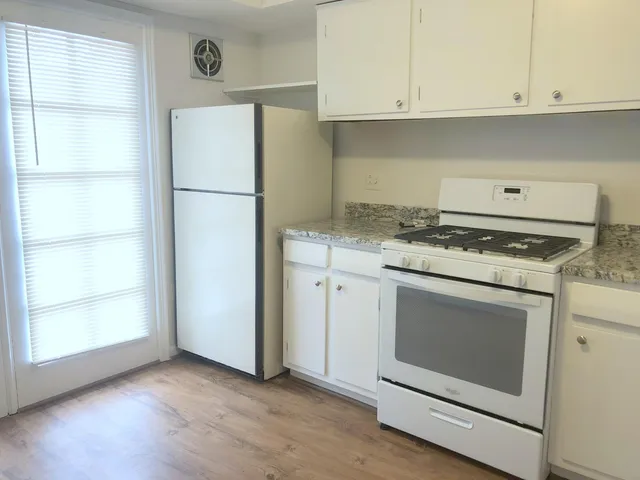 a kitchen with granite countertop white cabinets and white appliances