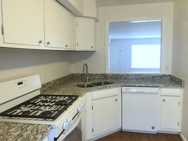 a kitchen with granite countertop a sink stove and cabinets