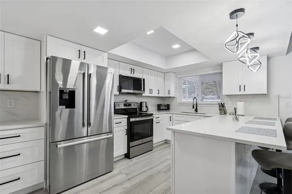 a kitchen with stainless steel appliances kitchen island granite countertop a sink and a refrigerator