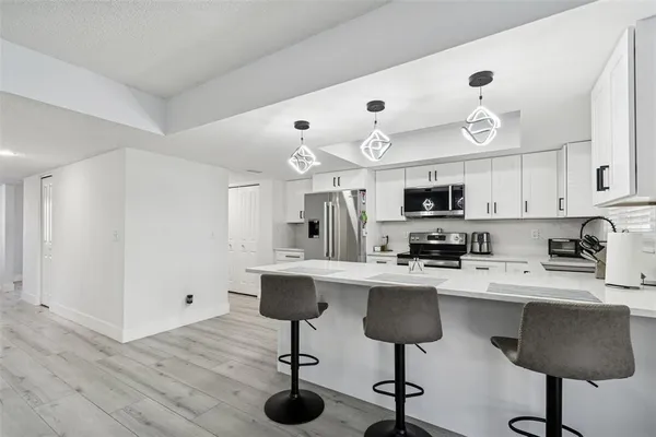 a kitchen with stainless steel appliances kitchen island granite countertop a table chairs sink and cabinets