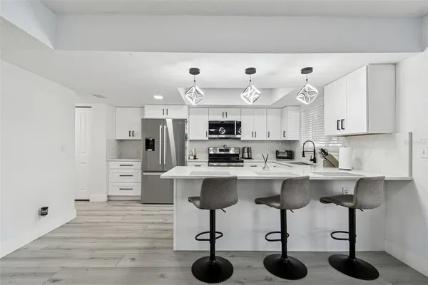 a kitchen with kitchen island white cabinets and stainless steel appliances