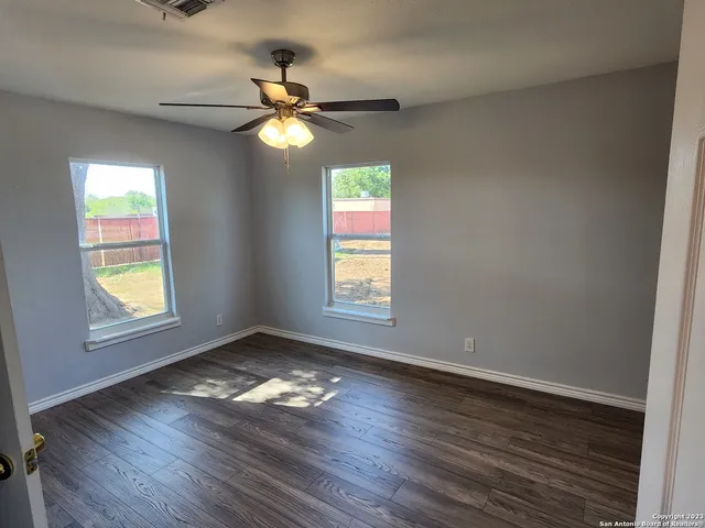 a view of empty room with wooden floor and fan