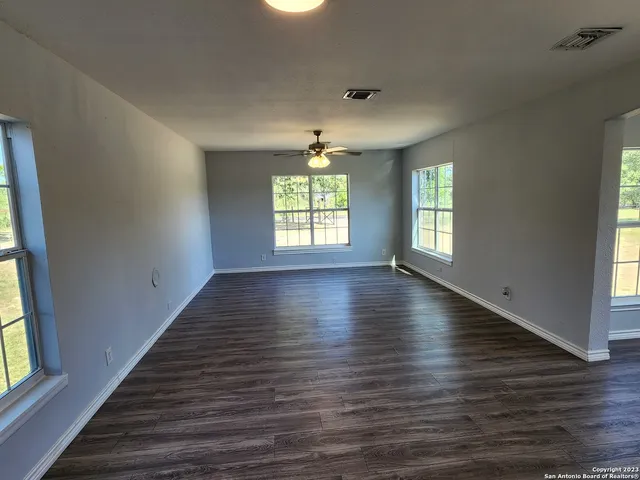 an empty room with wooden floor and windows