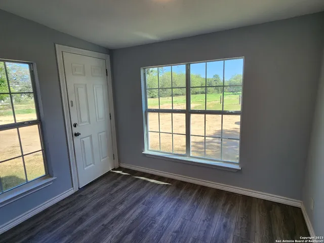 an empty room with wooden floor and windows
