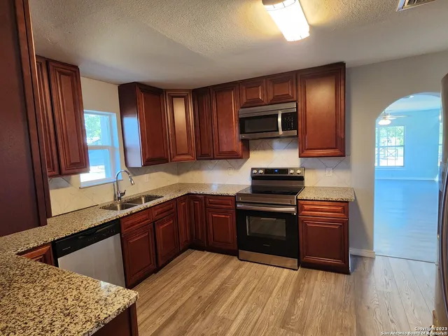 a kitchen with stainless steel appliances granite countertop a stove a sink and a microwave