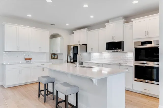 a large kitchen with granite countertop white cabinets and stainless steel appliances
