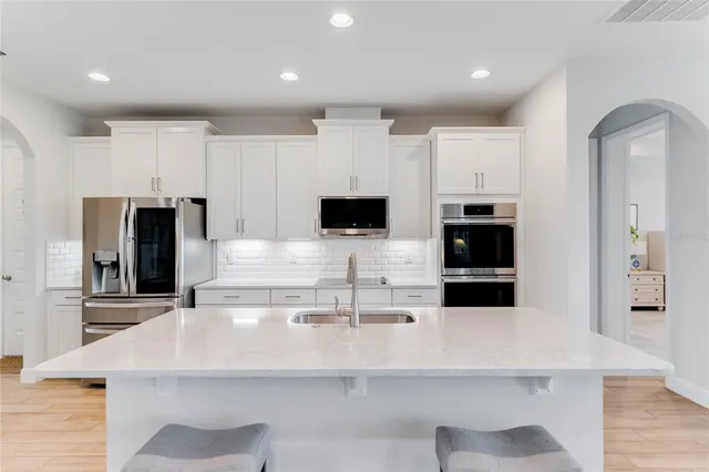 a kitchen with stainless steel appliances a microwave a stove and white cabinets
