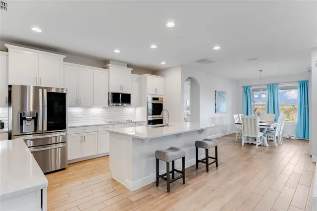 a large kitchen with cabinets chairs and stainless steel appliances