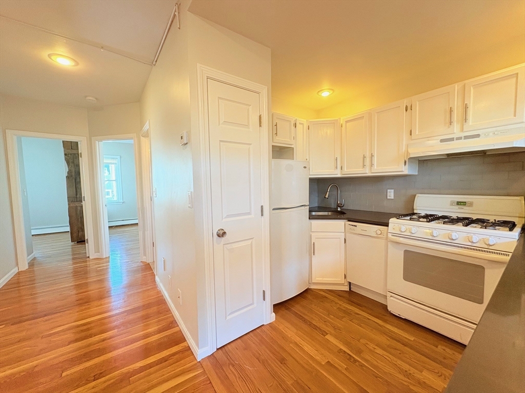 131 West Seventh Street, Unit 2 Boston, MA 02127 - Photo 3 of 11 a kitchen with granite countertop a refrigerator and a stove top oven