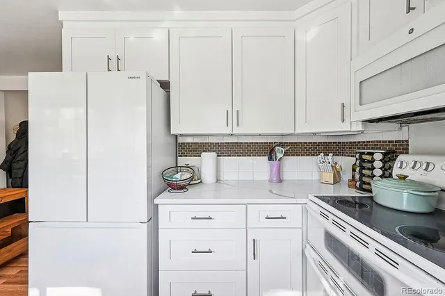 a kitchen with a refrigerator and white cabinets