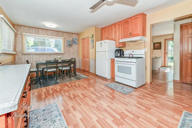 a open kitchen with stainless steel appliances granite countertop a refrigerator a stove top oven a dining table and chairs with wooden floor