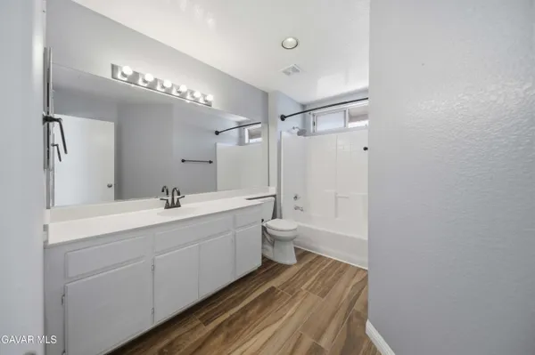 a bathroom with a double vanity sink a toilet and shower