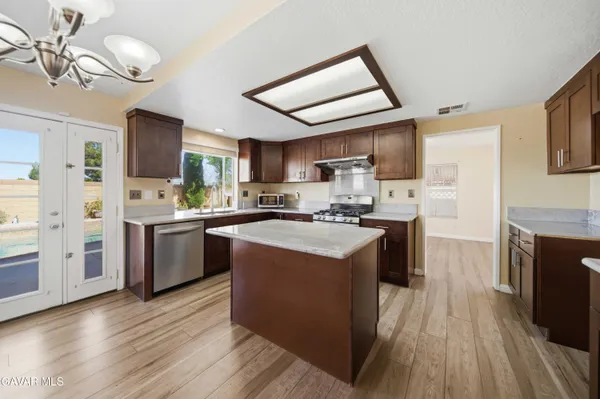 a kitchen with stainless steel appliances granite countertop a stove a sink dishwasher a refrigerator and a fireplace with wooden floor