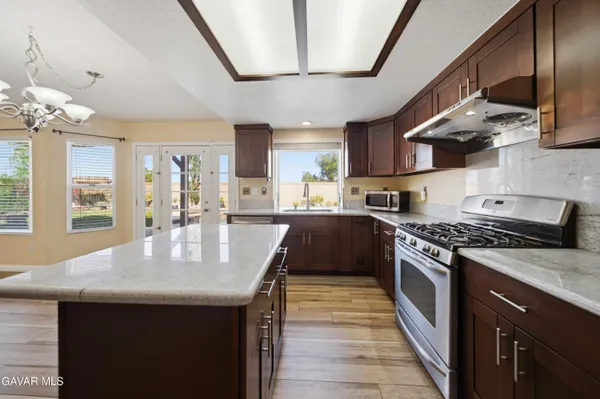 a kitchen with stainless steel appliances granite countertop a sink a stove and a wooden floors
