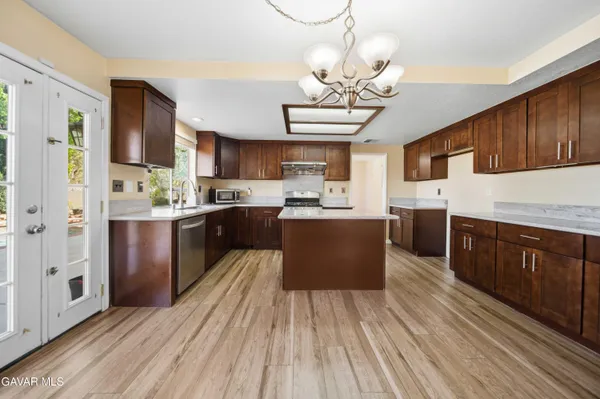 a kitchen with stainless steel appliances granite countertop a refrigerator a sink dishwasher a stove with wooden cabinets and floor