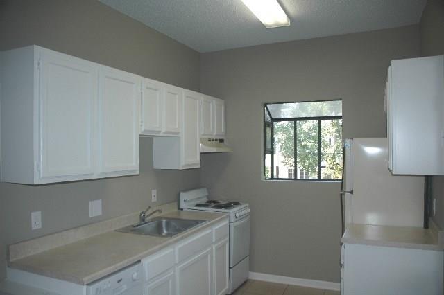 3206 King Street, Unit 202 Austin, TX 78705 - Photo 2 of 9 Kitchen with white appliances, white cabinetry, light countertops, and a textured ceiling