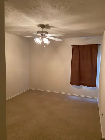 an empty room with windows and fan