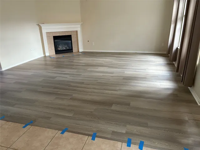 a view of empty room with wooden floor and fireplace